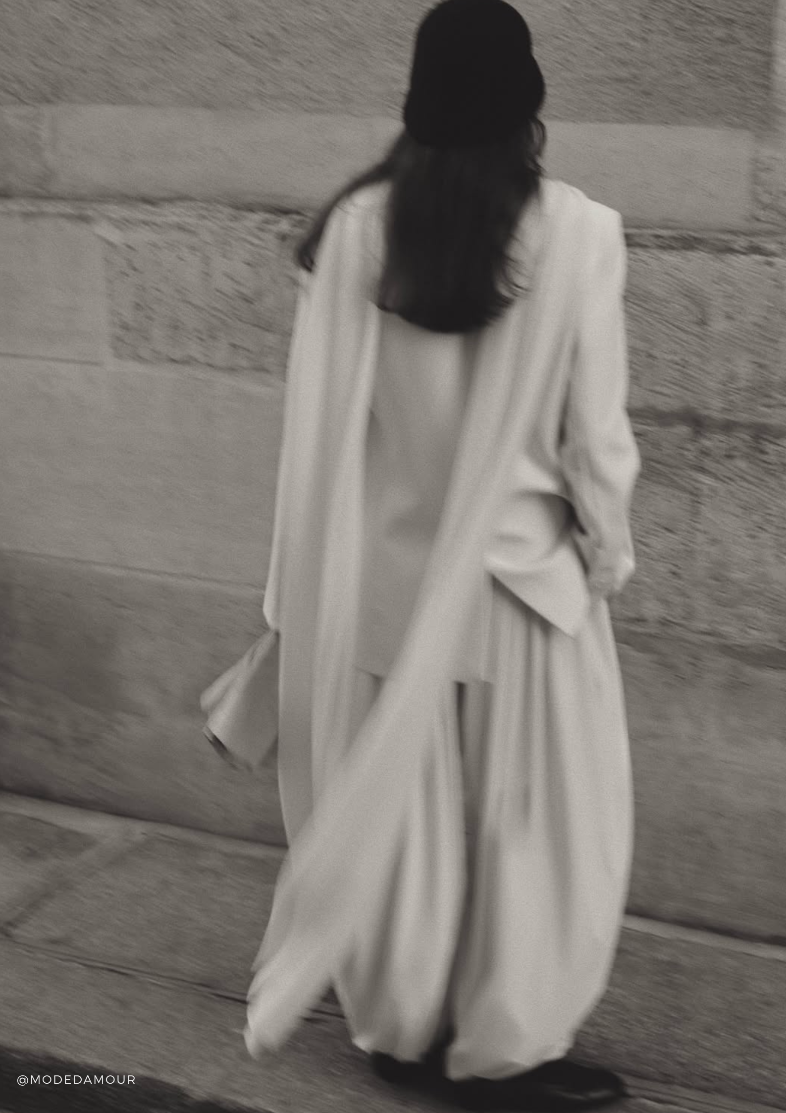 Woman wearing the SERENITY Chamonix extra-long white cashmere scarf draped over a monochrome white outfit.